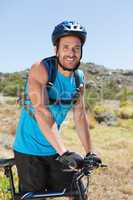 Fit cyclist riding in the countryside smiling at camera