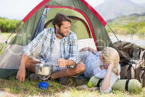 Attractive happy couple cooking on camping stove