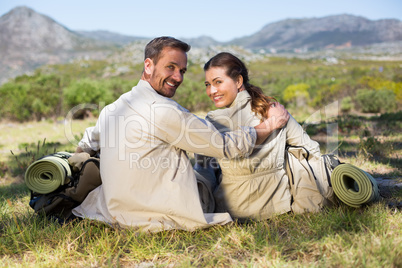 Hiking couple sitting and smiling at camera