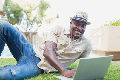 Handsome man relaxing in his garden using laptop