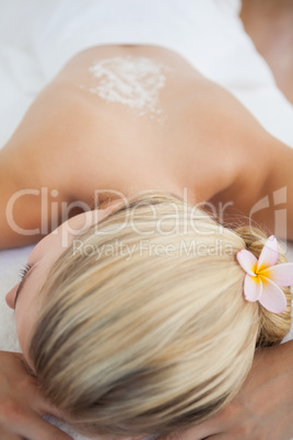 Beautiful blonde lying on massage table with salt scrub treatmen