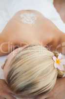 Beautiful blonde lying on massage table with salt scrub treatmen