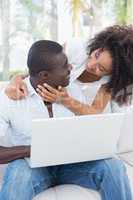 Attractive couple using laptop together on sofa