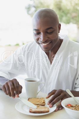 Handsome man in bathrobe having breakfast outside