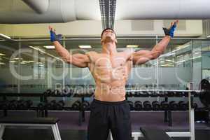 Bodybuilder with arms raised in gym
