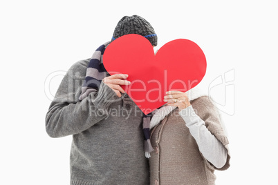 Happy mature couple in winter clothes holding red heart