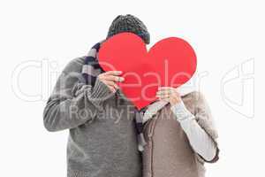 Happy mature couple in winter clothes holding red heart