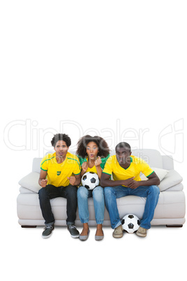 Nervous brazilian football fans in yellow on the sofa