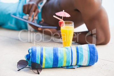 Shirtless man using his tablet pc with towel and sunglasses in f