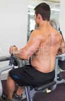 Muscular man working on abdominal machine at the gym