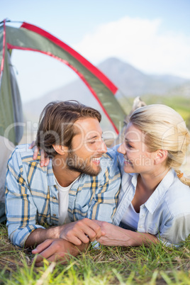 Attractive couple lying in their tent about to kiss