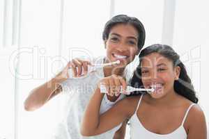 Pretty mother brushing her teeth with her daughter