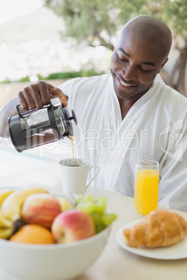 Handsome man in bathrobe having breakfast outside