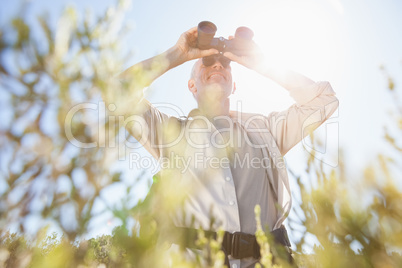 Hiker standing on country trail looking through binoculars