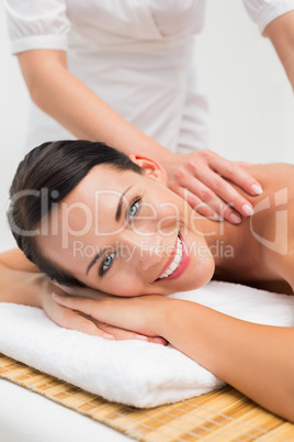 Beautiful brunette enjoying a shoulder massage smiling at camera