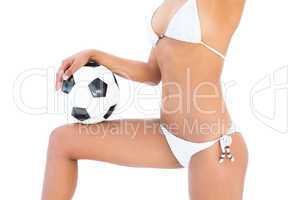 Fit girl in white bikini holding football