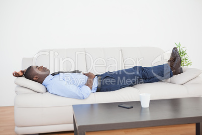 Tired businessman lying on the sofa