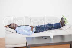 Tired businessman lying on the sofa