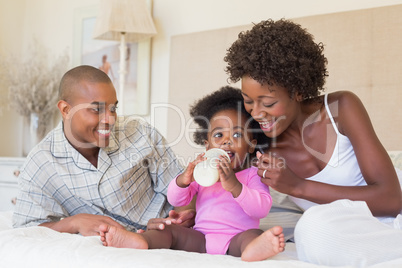 Happy parents with baby girl on their bed