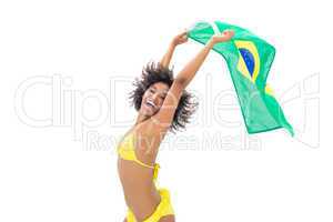 Fit girl in yellow bikini holding brazil flag laughing at camera