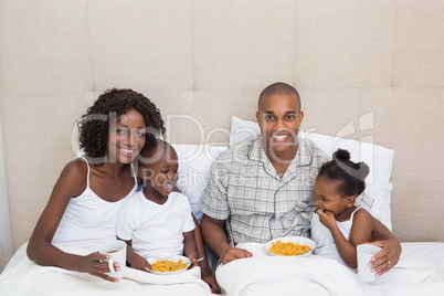 Happy family having breakfast in bed together in the morning