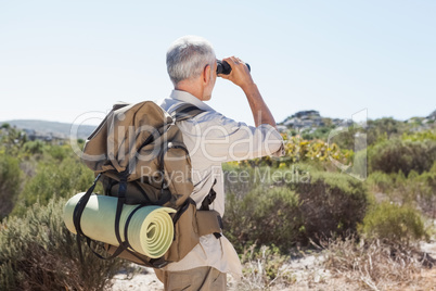 Hiker looking through binoculars on country trail