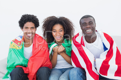 Football fans sitting on couch with flags