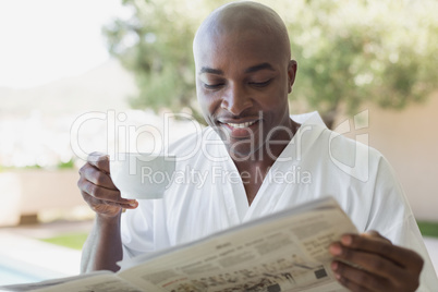 Handsome man in bathrobe having coffee outside