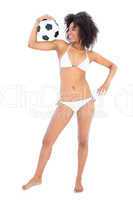 Happy fit girl in white bikini holding football