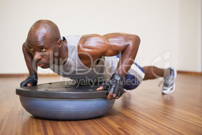 Muscular man doing push ups in gym