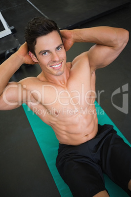 Muscular man doing abdominal crunches in gym