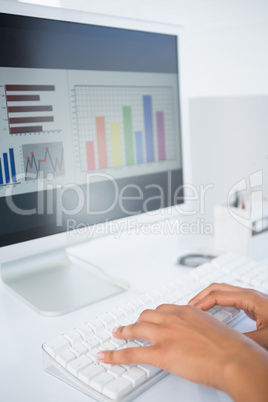 Businesswoman typing on a keyboard with data on screen