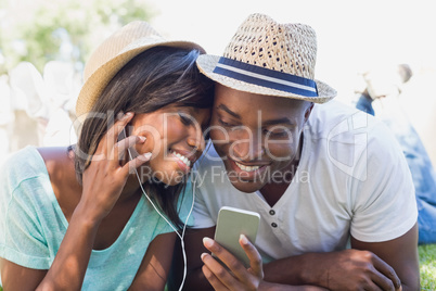 Happy couple lying in garden together listening to music