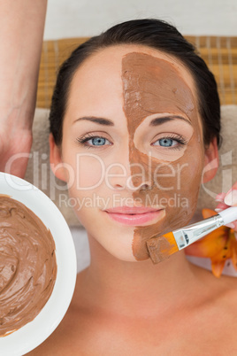 Peaceful brunette getting a mud facial applied