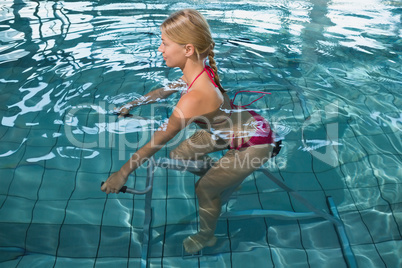 Fit happy blonde using underwater exercise bike