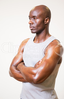 Serious muscular man with arms crossed looking away