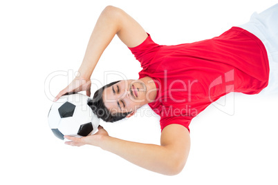 Football player in red lying with ball