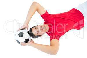 Football player in red lying with ball