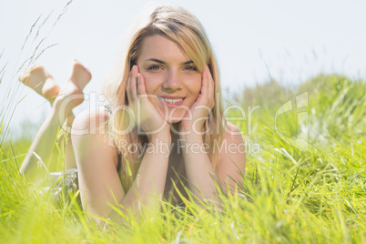 Pretty blonde in sundress lying on grass smiling at camera