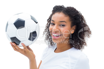 Pretty football fan in white holding ball smiling at camera