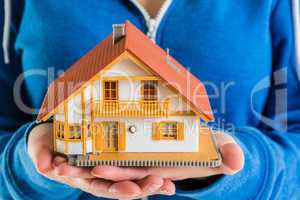 Hands holding miniature house model