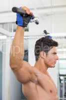 Shirtless male body builder doing pull ups at the gym