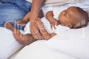 Happy father napping with baby son on couch