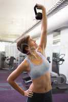 Fit brunette lifting kettlebell and smiling