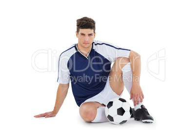 Football player sitting on the ground with ball