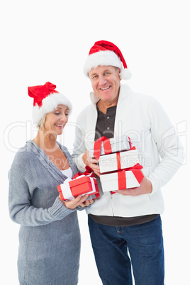 Festive mature couple in winter clothes holding gifts