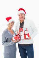 Festive mature couple in winter clothes holding gifts