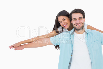 Happy casual man giving pretty girlfriend piggy back