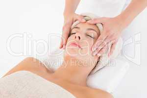 Attractive young woman receiving facial massage at spa center