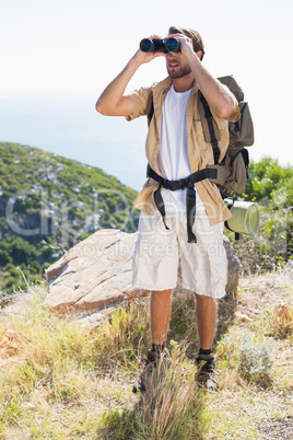 Handsome hiker looking through binoculars